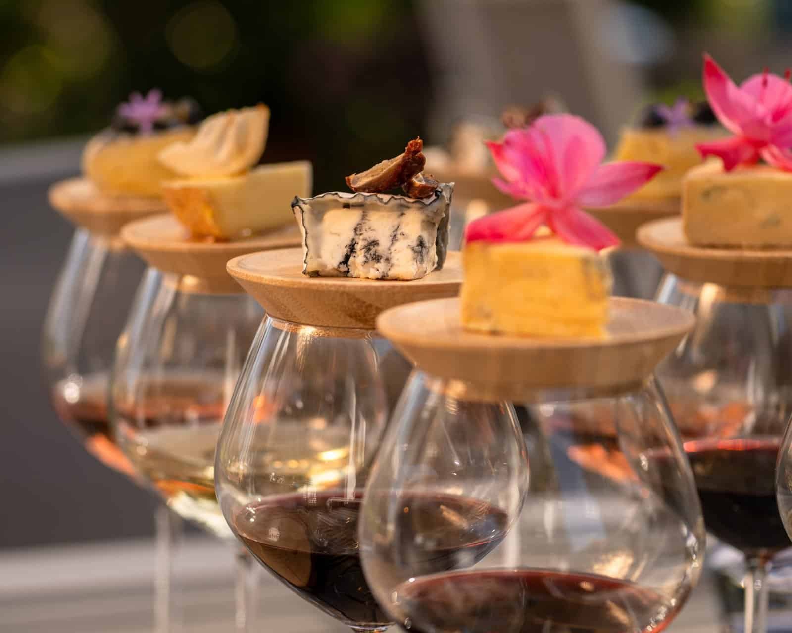 Assorted gourmet cheeses with edible flowers served on wooden pegs at Palm House Boutique Hotel and Spa, perfect for a luxury wine and dine experience.