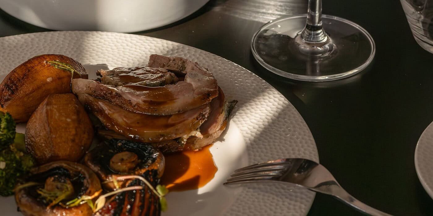 Delicious gourmet meal featuring roasted meats, fresh vegetables, and a glass of red wine at Palm House Boutique Hotel and Spa in South Africa, offering exquisite dining experiences.