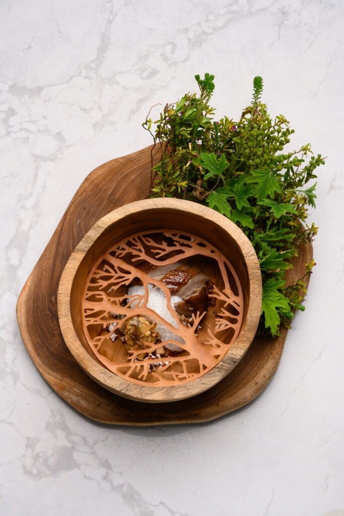 Scented candle with wood and green plant decor at Palm House Boutique Hotel and Spa in South Africa.