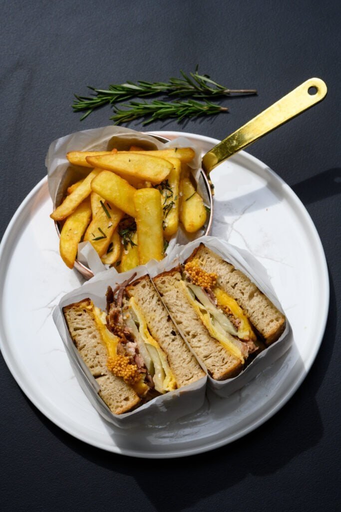 Crispy club sandwich with fries and mustard, served at Palm House Boutique Hotel and Spa.