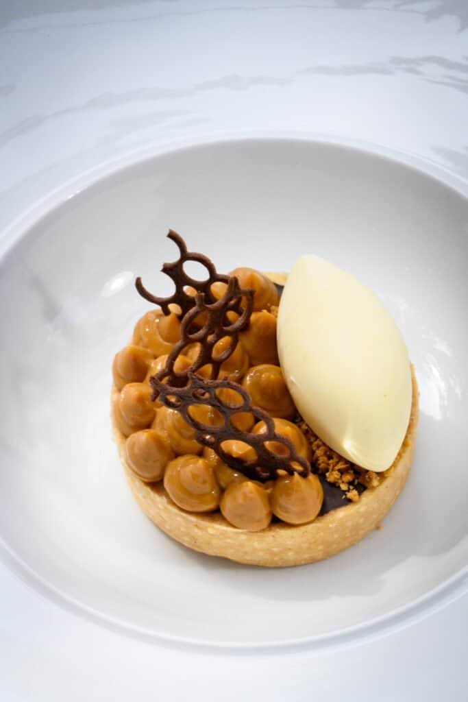 Velvet caramel tart with white chocolate ice cream, featuring intricate chocolate decorations, served at Palm House Boutique Hotel and Spa, a luxury accommodation in South Africa.