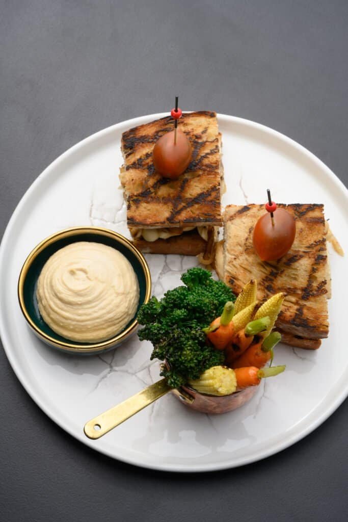 Succulent grilled “pork belly” with creamy mashed potatoes, fresh vegetables, and garnished with cherry tomatoes served at Palm House Boutique Hotel and Spa in South Africa.